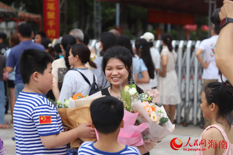 小朋友們手捧鮮花迎接姐姐。人民網(wǎng) 牛良玉攝