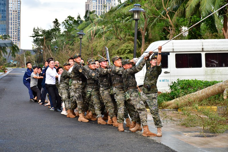 在災后重建工作中，武警海口支隊官兵和群眾一起移除砸壞車輛的樹木。袁琳松攝